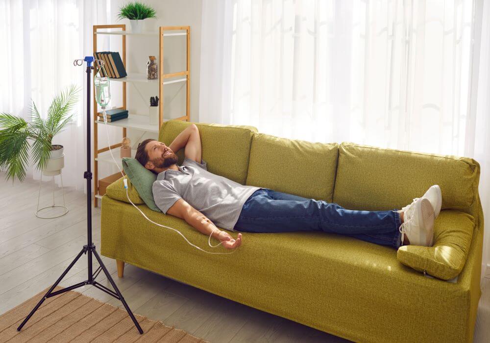 Man lying on a green sofa while undergoing hydration therapy