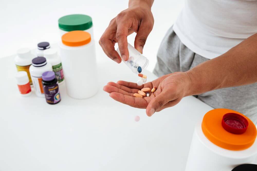 A person shaking pills out of a plastic container into his hand